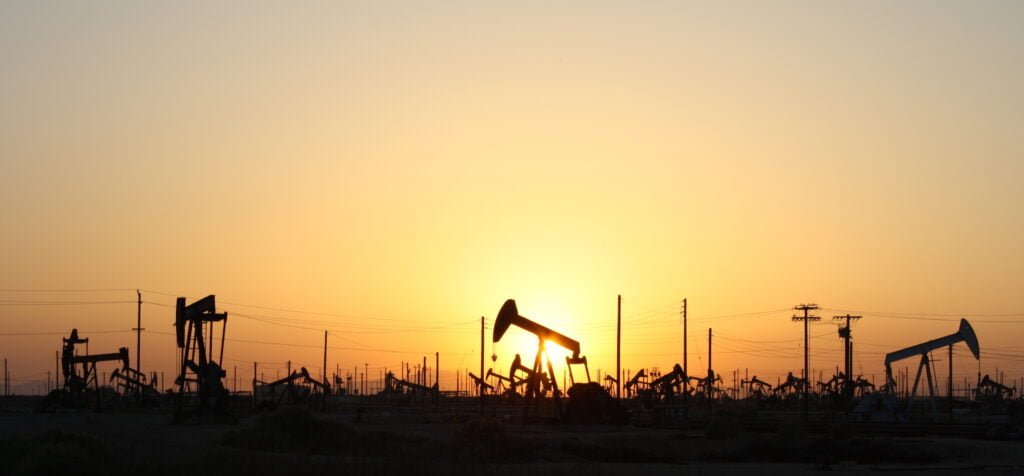 A sucker rod pump producing oil at sunset