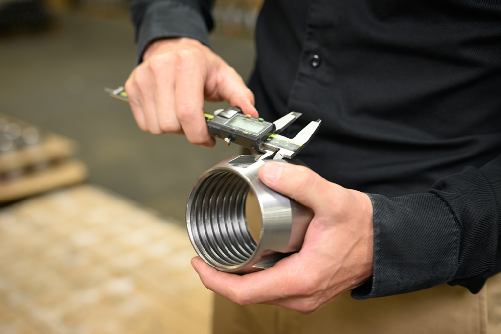 A man measures the size of a tubing anchor catcher component