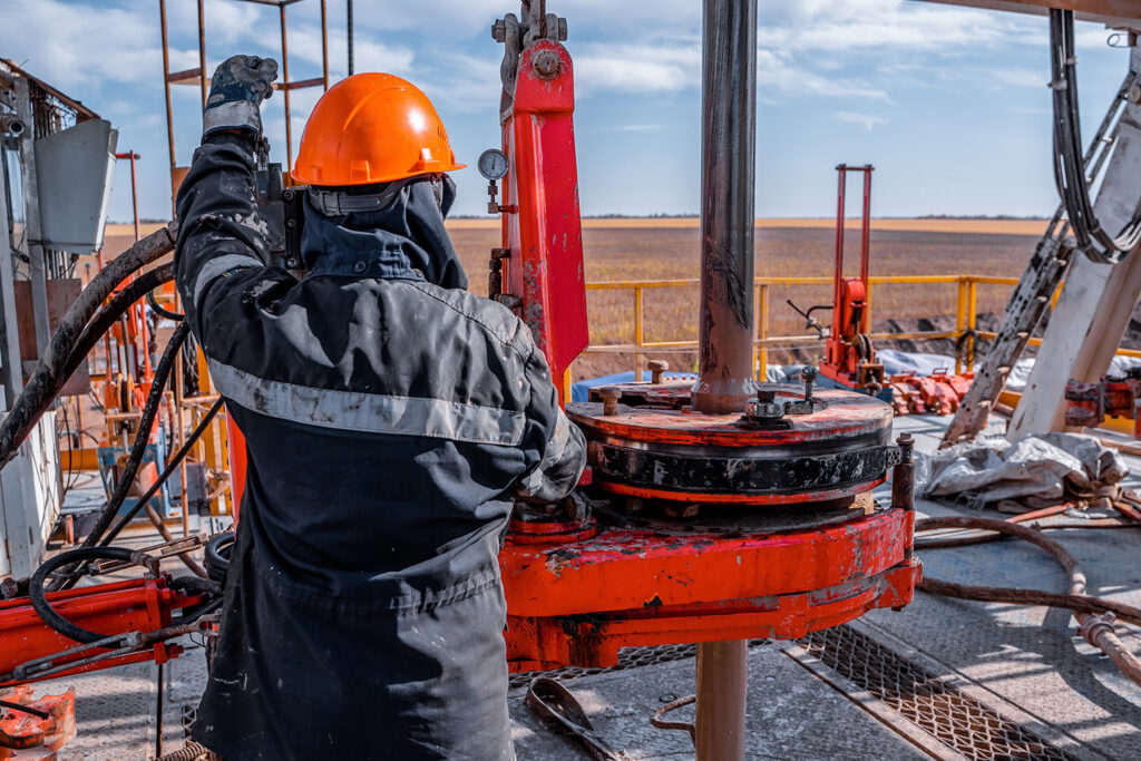 An oil rig worker operating a hydraulic wrench