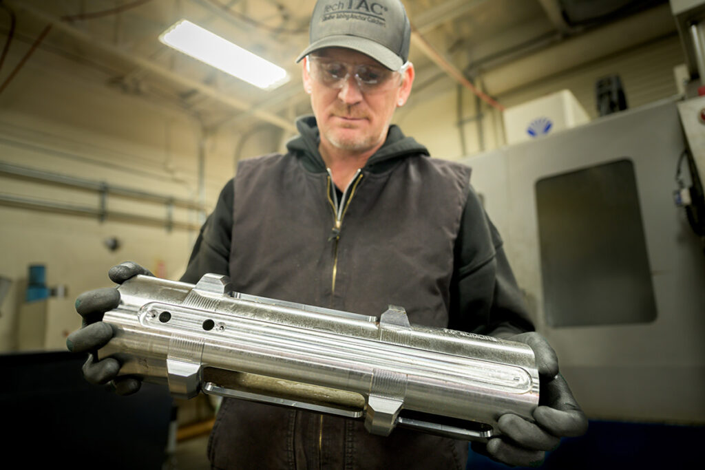 A TechTAC machinist holds a Slimline TAC housing