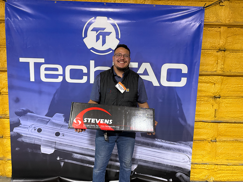A man holding a new shotgun still in the box.